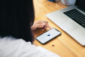 donna con mano su smartphone con PayPal e pc