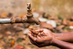 mani di persona e rubinetto arrugginito senza acqua